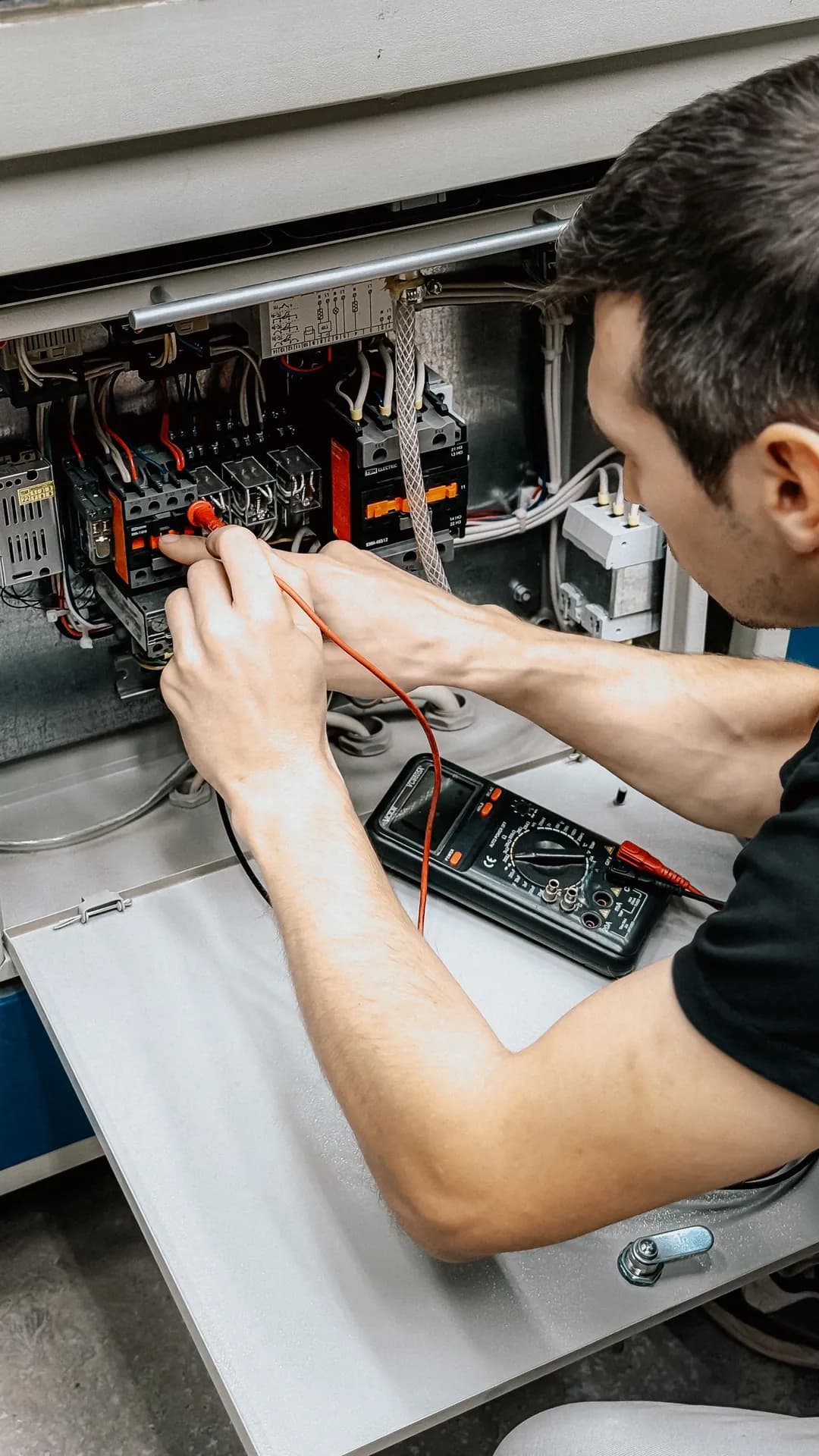 Engineer diagnosing an electrical panel with a multimeter
