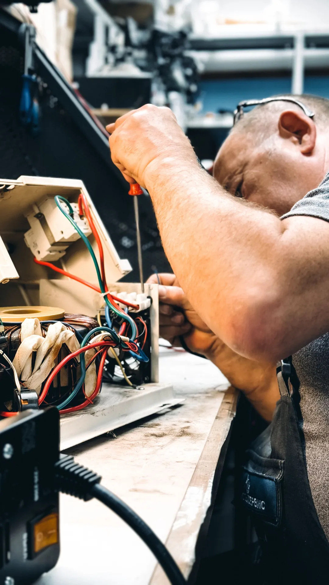Electrician repairing equipment at a workshop bench